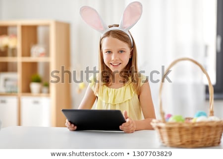 Foto stock: Happy Girl With Tablet Pc And Easter Eggs At Home