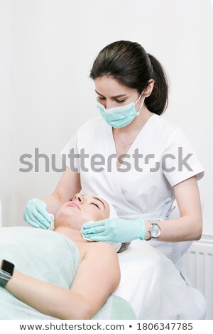 Stockfoto: Female Cosmetologist Cleansing Client Face With Sponge