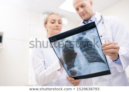 Foto stock: X Ray Of Lungs Or Spinal Cors Held By One Of Doctors During Consultation