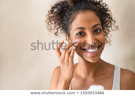 Foto stock: Close Up Of Woman Applying Face Cream At Bathroom