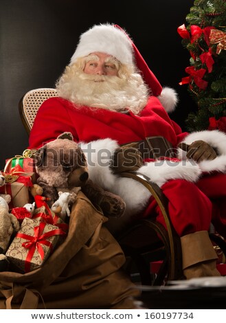 Stockfoto: Santa Claus Sitting In Rocking Chair Near Christmas Tree At Home