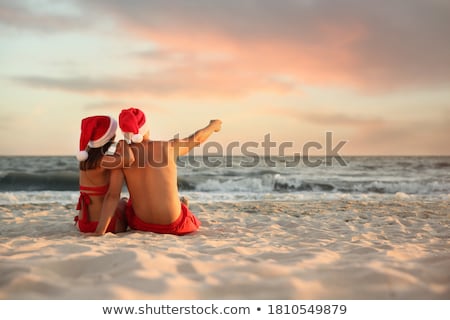 Stock foto: Young Loving Couple Sitting Outdoors In Evening In Christmas Hat Holding Gift Box Take A Selfie By C