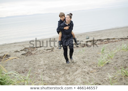 Сток-фото: Family Enjoying The Rain And Having Fun Outside On The Beach A Gray Rainy