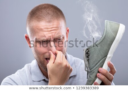 Stok fotoğraf: Man Covering His Nose While Holding Stinky Shoe