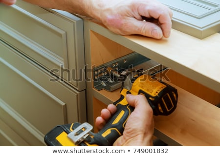 [[stock_photo]]: Workman Fixes A Hinge To A Kitchen Cabinet