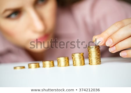 Stok fotoğraf: Woman Stacking Gold Coins Into Increasing Columns