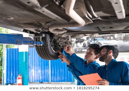 Foto stock: Female Mechanic Repairing Suspension System Of Car In Garage