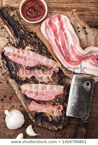 Foto stock: Grilled Bacon Strips On Vintage Wooden Board With Raw Fresh Smoked Pork Bacon On Butchers Paper On W