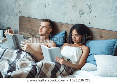 Stockfoto: Couple Reading A Book In Bed