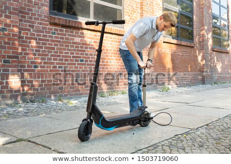 Stock photo: Man Pumping Air Into Tire On E Scooter