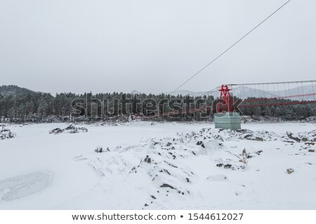 Stok fotoğraf: Suspension Hanging Bridge Above Winter Frozen River