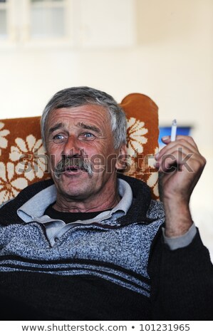 Old Man With Mustache Smoking Cigarette While Sitting In Sofa And Speaking Foto stock © Zurijeta