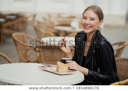 Stockfoto: Smiling Blonde Woman In Leather Jacket Resting On A Chair