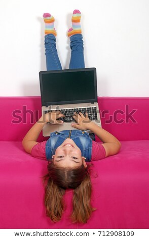 Stock photo: Happy Little Girl With Laptop Lying Upside Down On Bed