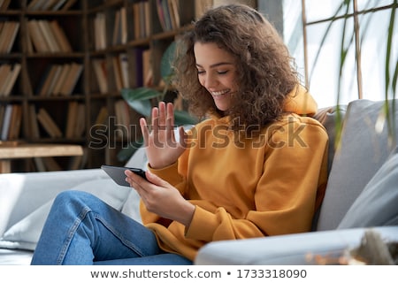 Stockfoto: Smiling Young Woman Waving To Friends Talking By Phone