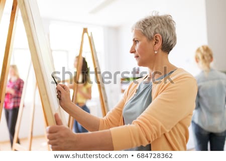 Foto stock: Senior Woman Drawing On Easel At Art School Studio