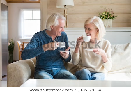 ストックフォト: Smiling Casual Couple Sitting On Couch Having Coffee