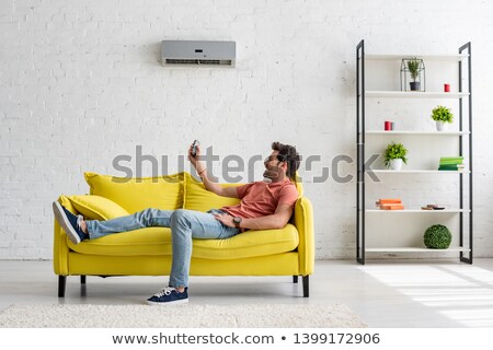 Stockfoto: Man Relaxing On Sofa Under Air Conditioner