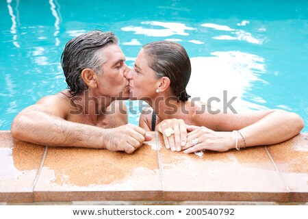 Stok fotoğraf: Senior Couple Kissing By Swimming Pool