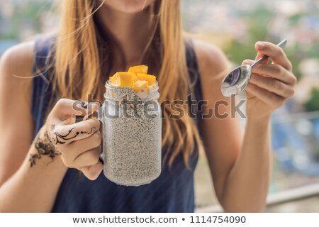 Foto stock: Young Woman With Mehendi From Henna On Hand Eating Chia Pudding On Her Balcony Overlooking The Big C