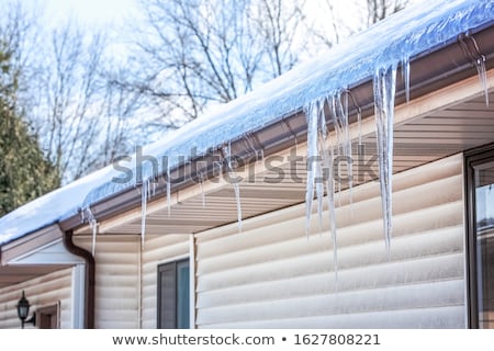 Foto stock: Heat Loss - Icicles Hanging On House Roof