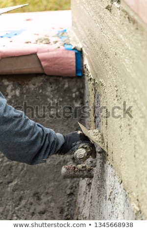 Stockfoto: Tile Worker Applying Cement With Trowel At Pool Construction Sit