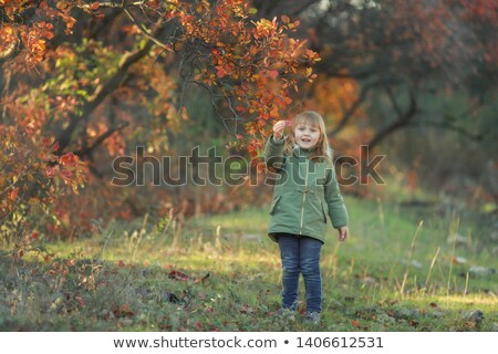 Stock photo: Funny Kid Girl Pretending To Be Posing In Autumn Forest Wearing A Green Coat