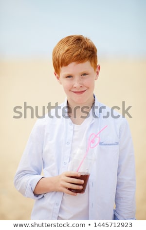 商業照片: Boy With Red Hair Is Thirsty And Drinks With A Straw