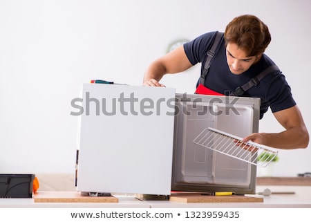 Stok fotoğraf: Young Handsome Contractor Repairing Fridge