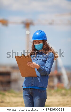 Сток-фото: Young Businesswoman Wearing Engineer Hat Holds Blue Clipboard