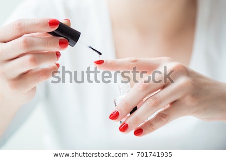 Foto d'archivio: Young Woman Applying Red Nail Polish To Her Fingernails