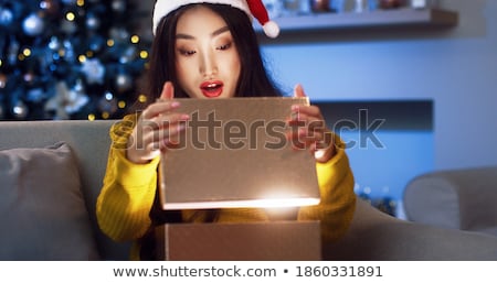 Stock photo: Close Up Portrait Of An Excited Young Woman Opening Present Box While Lying In Bed At Home