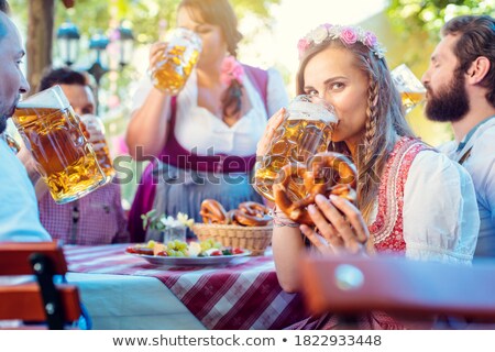 Stockfoto: Woman In Tracht Looking Into Camera While Drinking A Mass Of Beer