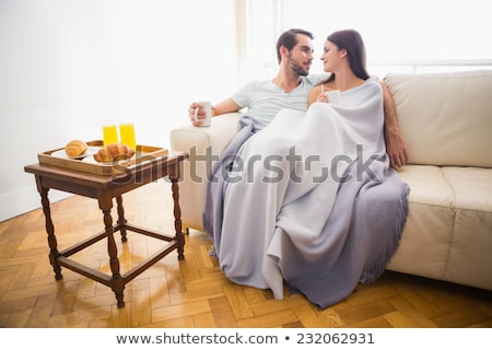 Stockfoto: Young Couple Cuddling On The Couch Under Blanket