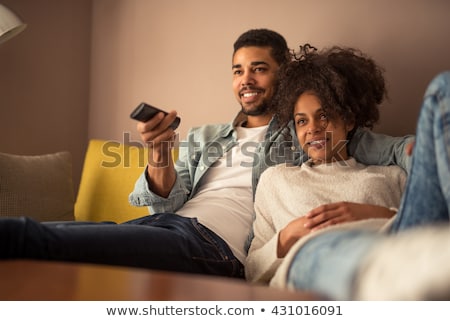 Foto d'archivio: Young Happy Woman Lying On The Sofa With Remote Control At Home