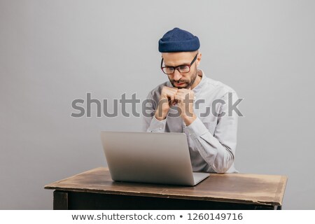 [[stock_photo]]: Serious Male Workaholic Sits At Desktop With Modern Electronic Device Watches Video Prepares Finan