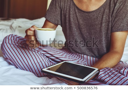 ストックフォト: Young Man In Bed Reading An E Book In His Tablet