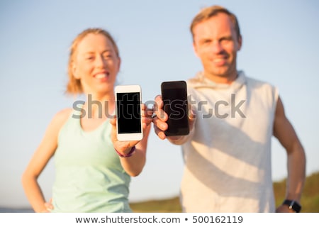 Foto stock: Couple With Phones And Arm Bands Running On Beach