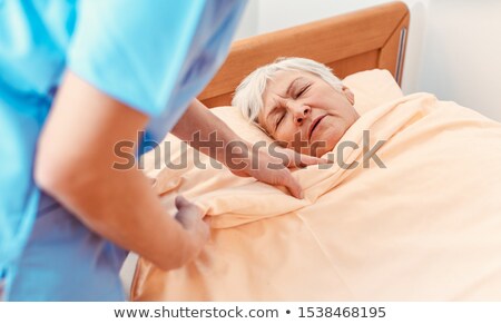 Stockfoto: Caregiver Pulling Blanket Over Sleeping Senior In Pensioners Home