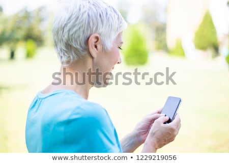 Foto d'archivio: Senior Woman In Sports Clothing Using Smart Phone Outdoor