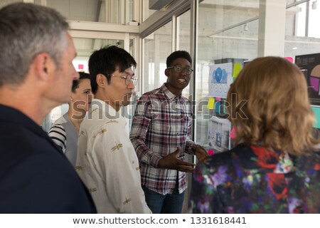 Stockfoto: Side Vew Of Standing Mixed Race Business Colleagues Interacting With Each Other In Modern Office