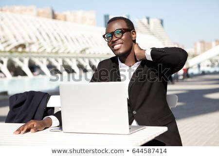 Foto d'archivio: Hand Of Young Man Holding Smartphone Over Table While Sitting In Front Of Laptop