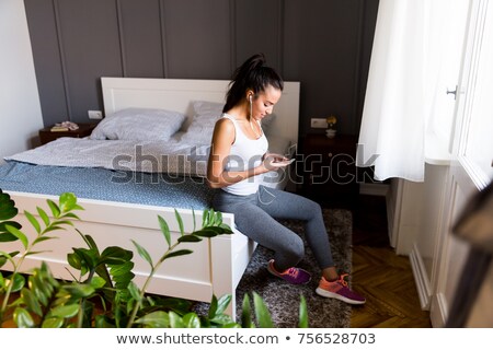 商業照片: Young Fit Woman Is Browsing Her Mobile Phone Andlooking For Her