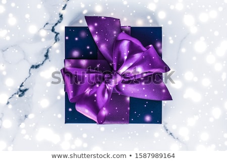 ストックフォト: Winter Holiday Gift Box With Purple Silk Bow Snow Glitter On Ma