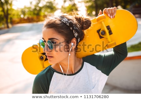 [[stock_photo]]: Pretty Woman Holding Skateboard Outdoors Looking Aside