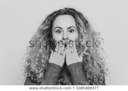 Stok fotoğraf: Emotional Lovely Woman With Unexpected Look Covers Mouth With Hand Has Red Manicure Curly Hair Is