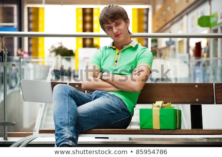 Stok fotoğraf: Portrait Of Young Man Inside Shopping Mall With Gift Box Waiting