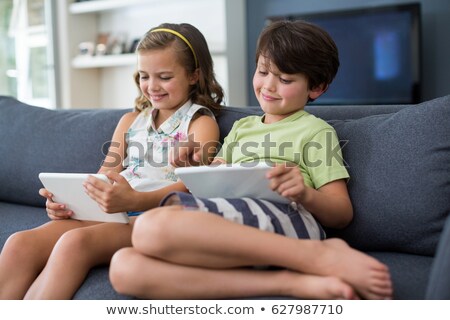 Foto d'archivio: Brothers And Sister Using Technologies On Sofa