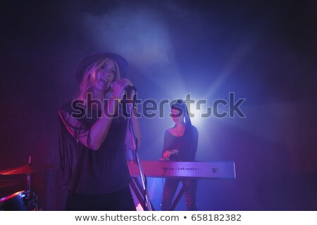 Zdjęcia stock: Female Singer Singing While Musician Playing Piano In Illuminated Nightclub