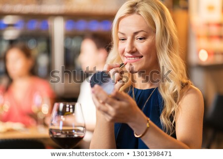 Stockfoto: Woman With Lipstick Applying Makeup At Wine Bar